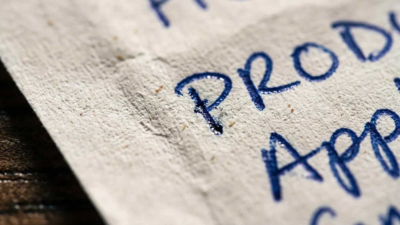 Liste de courses manuscrite posée sur un plan de travail, organisée par rayons