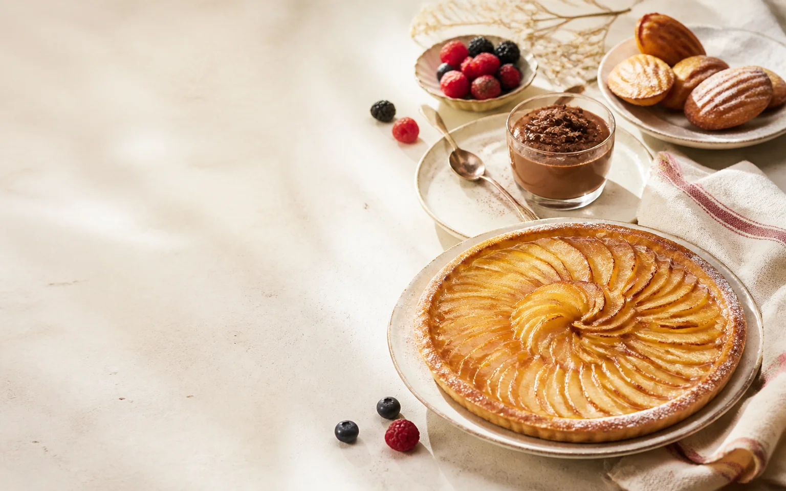 Tarte aux pommes dorée avec mousse au chocolat, madeleines et fruits rouges