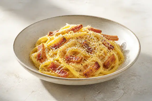 Spaghetti carbonara traditionnelle crémeuse avec guanciale croustillant, pecorino et poivre noir